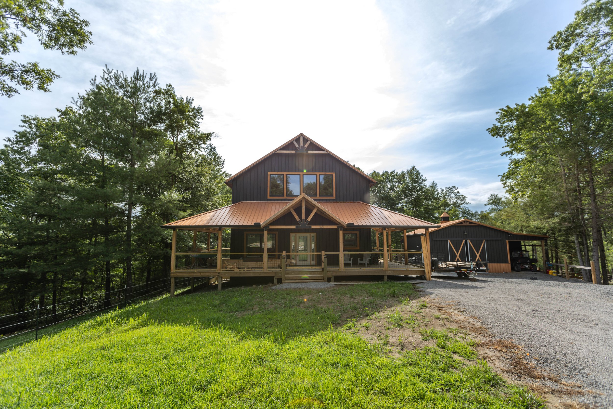 Completed custom barndominium with wraparound porch and copper standing-seam roof